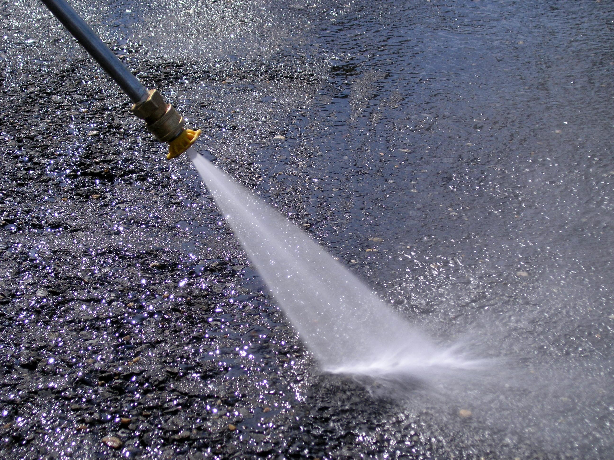 Pressure washing an outdoor hard surface with a high pressure water spray